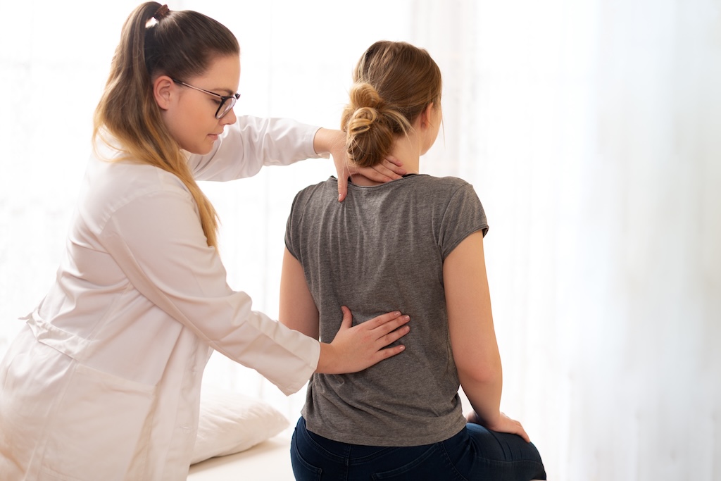 Female physiotherapist or a chiropractor examining patients back. | Doc Sawyer Chiropractic Female physiotherapist or a chiropractor examining patients back.